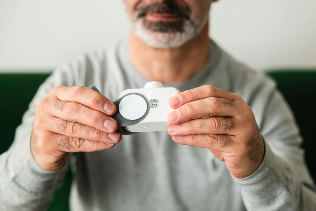 A person pressing the test button on a ceiling-mounted smoke alarm.