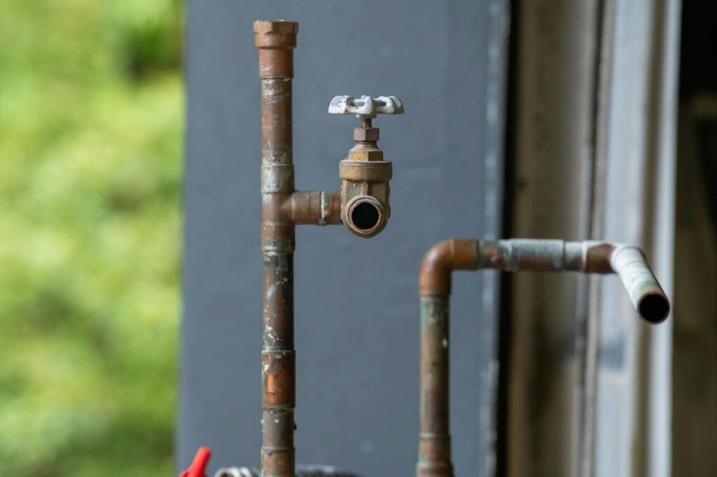Close-up view of shutoff valves, supply lines, and a drain trap under a sink