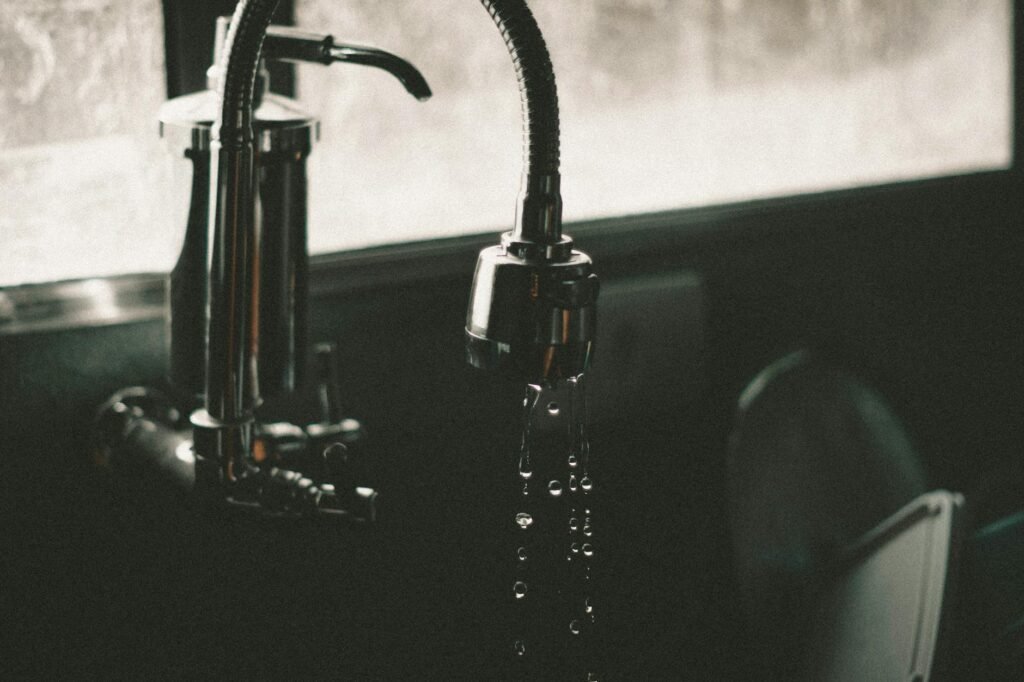 A homeowner inspecting the cabinet under a kitchen sink with a flashlight and a small checklist.