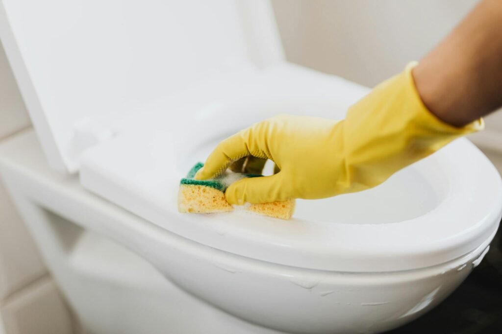 A hand drops dye into a toilet tank to test for a silent leak.