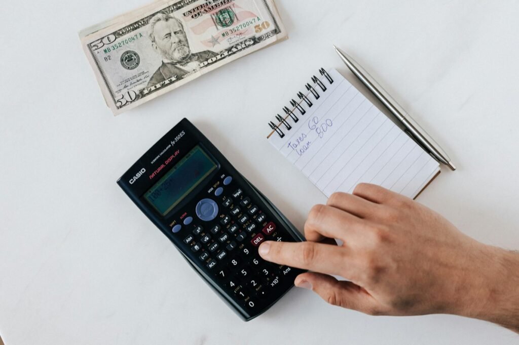 A water bill, calculator, and notes beside small toilet repair parts.