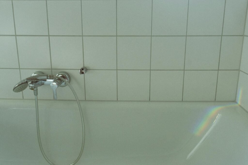 Worn caulk and grout where a bathtub meets a tiled wall