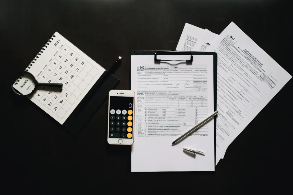 A desk with plumbing estimates, a calculator, a calendar, and an appliance manual.