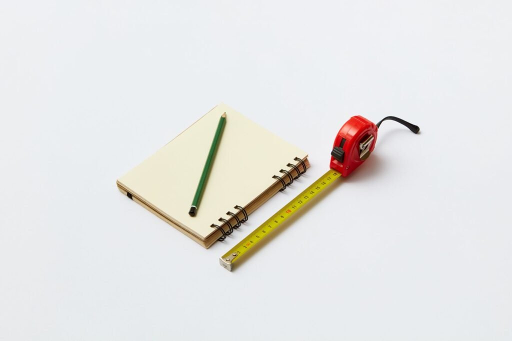 A notebook and calculator beside caulk and a utility bill on a desk.