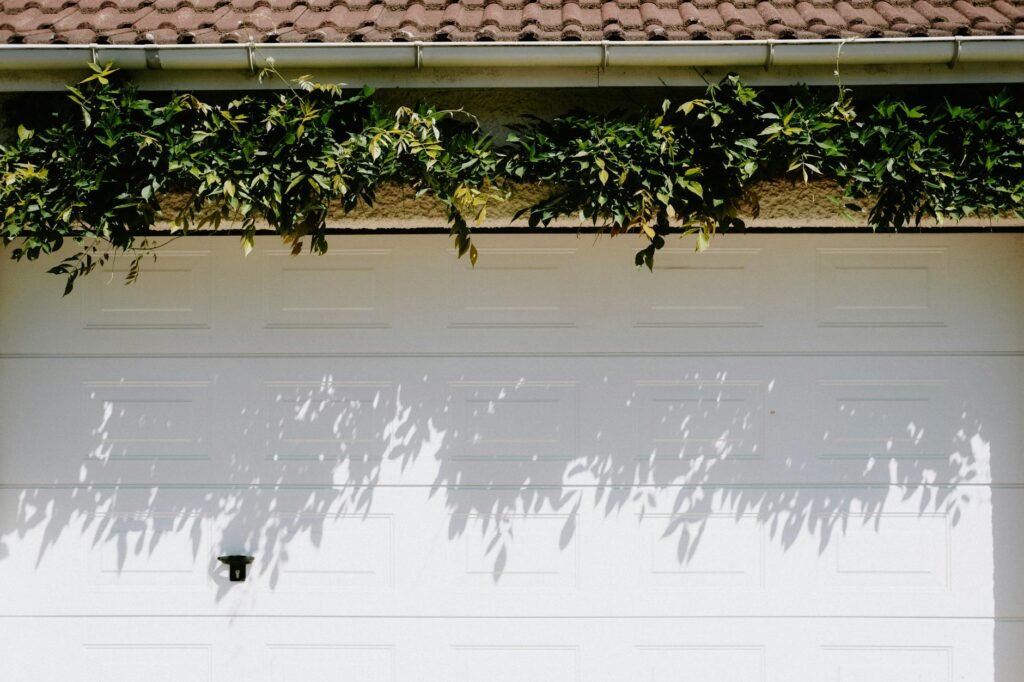 Close-up of a garage door safety sensor being cleaned near the floor track.