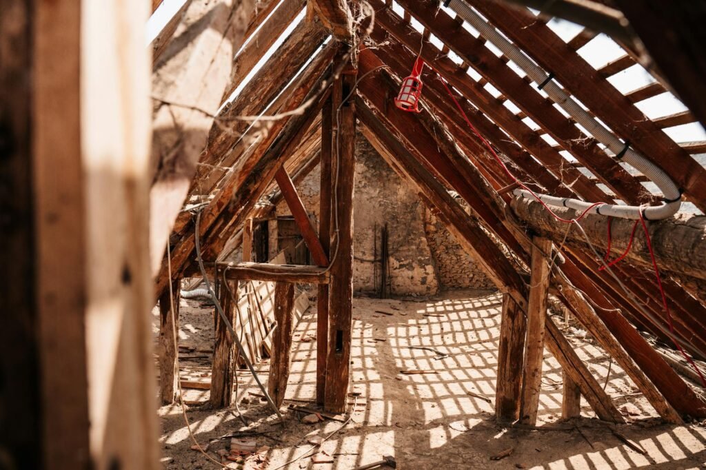 A flashlight illuminating insulation and roof framing inside an unfinished attic.