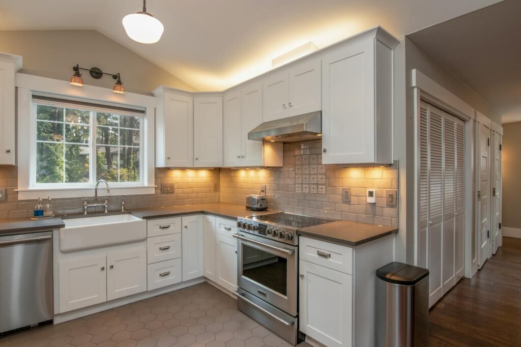 Hands removing a metal range hood filter for cleaning at a kitchen sink